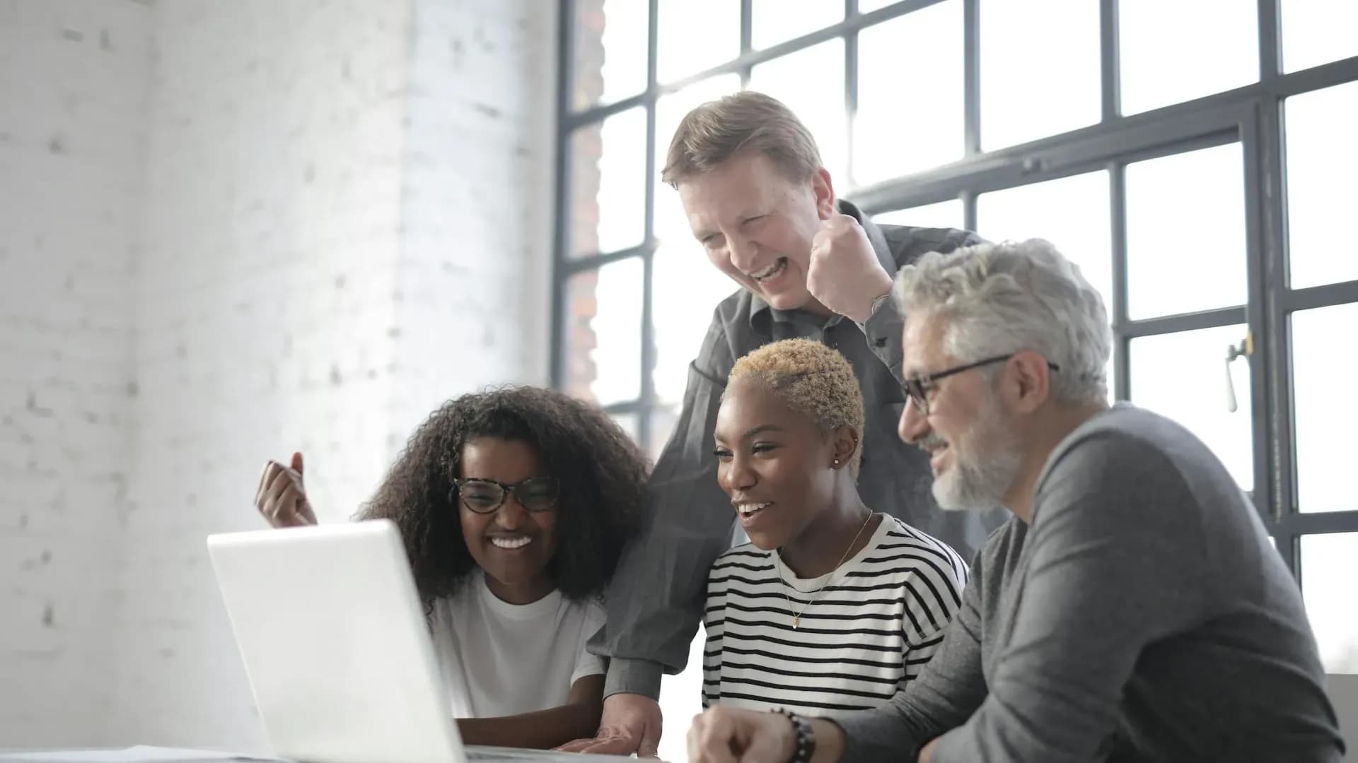 Diverse team celebrating their first AI win together around a laptop