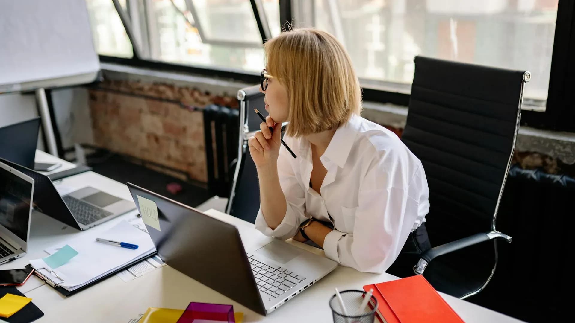 Woman thinking while comparing AI tools on her laptop