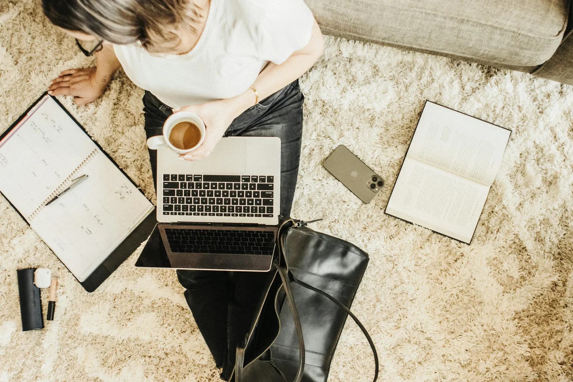 Woman working comfortably at a tidy desk with laptop and coffee, calm and unhurried