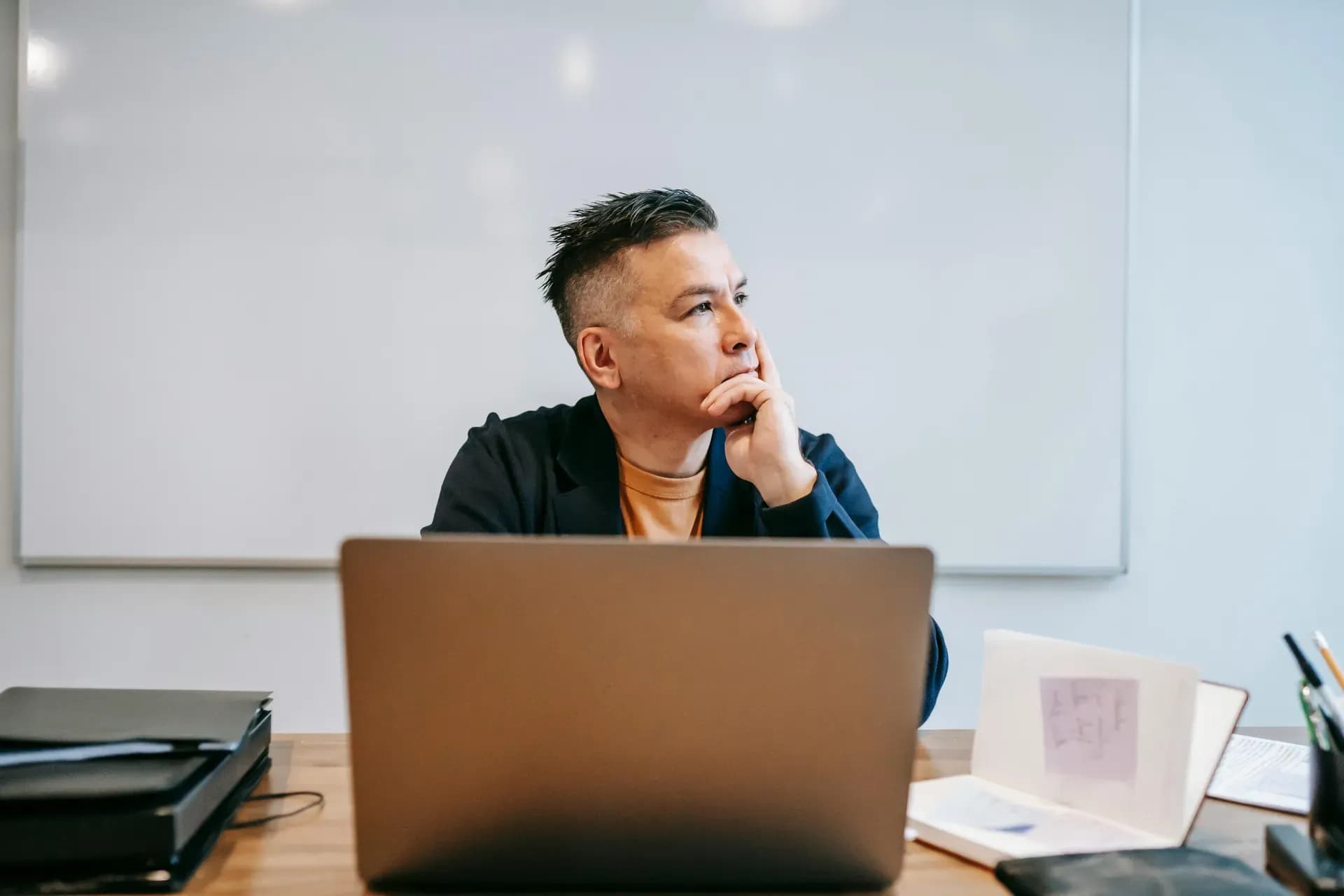 Businessman in home office, sitting in deep thought at his desk — reflecting on the ethics of using AI at work