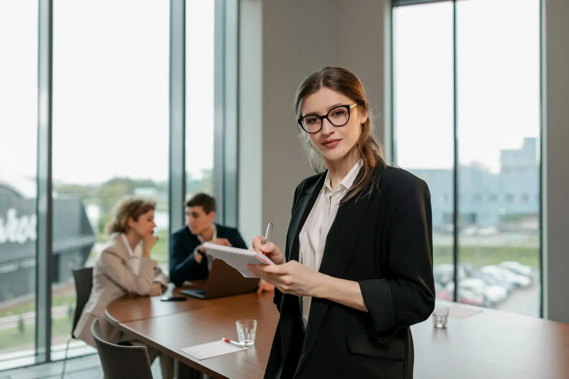 Mid-career professional woman in a black blazer holding a notebook, ready to start learning AI