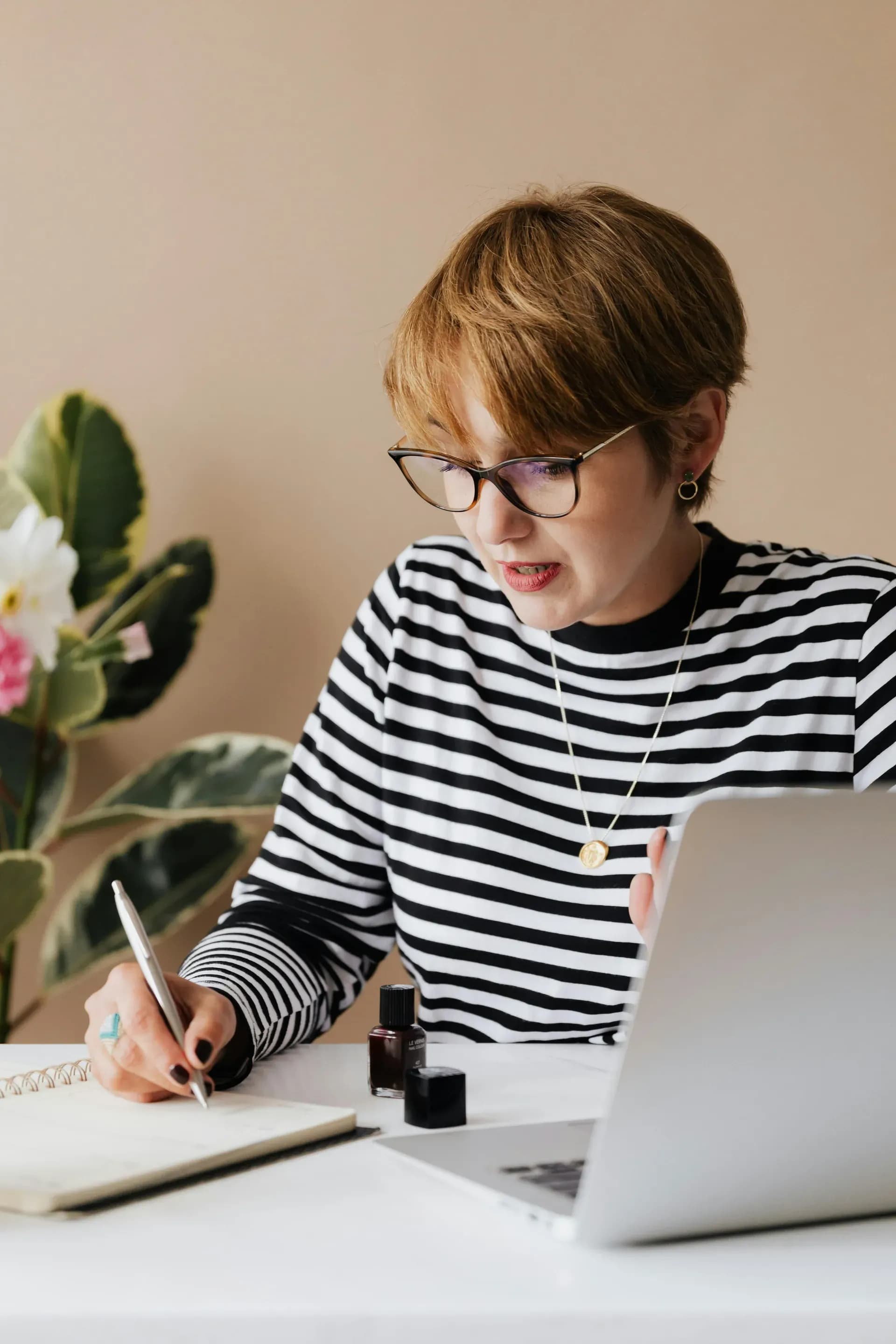 Focused woman writing notes in a notebook, drafting a clear brief