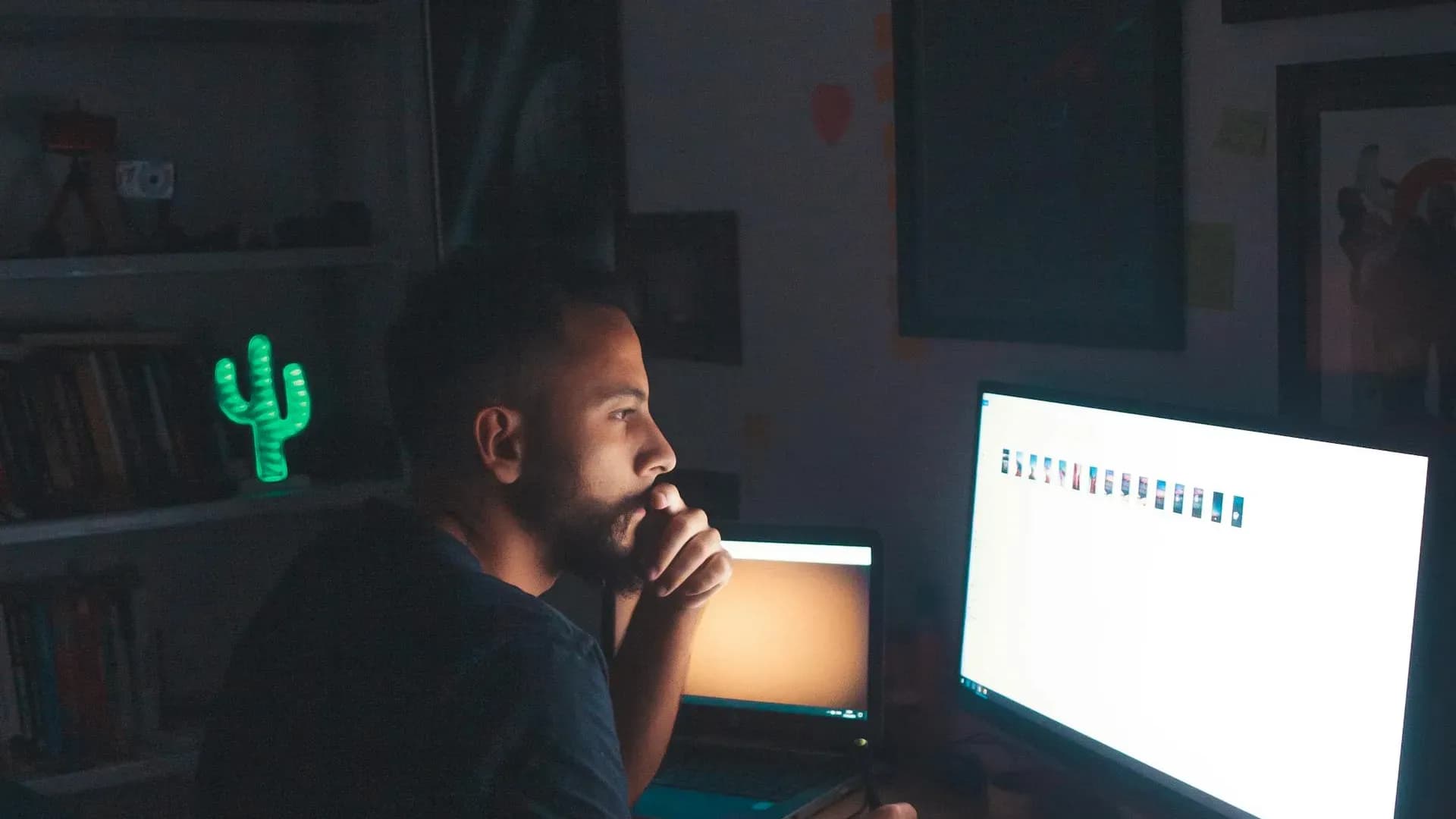 Thoughtful man studying computer screen in a dimly lit home office